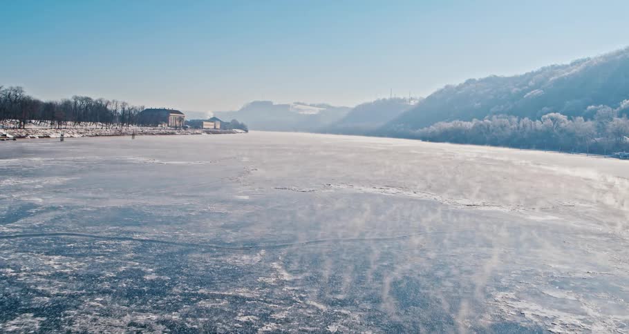 A large river is frozen over under a bridge