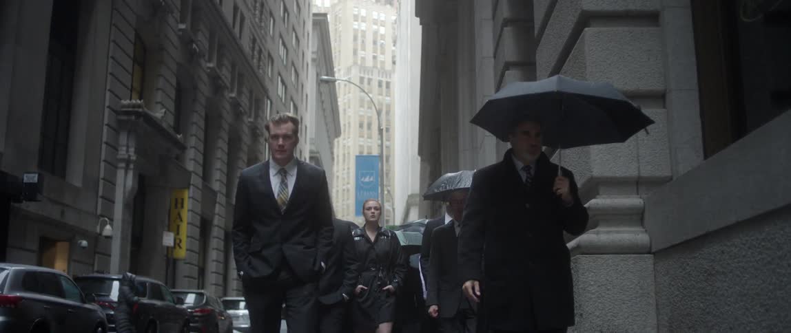 People in suits walk down a city street