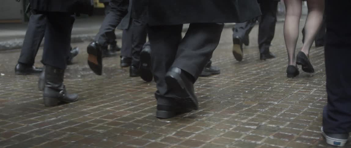 People walking along a wet, brick-paved street