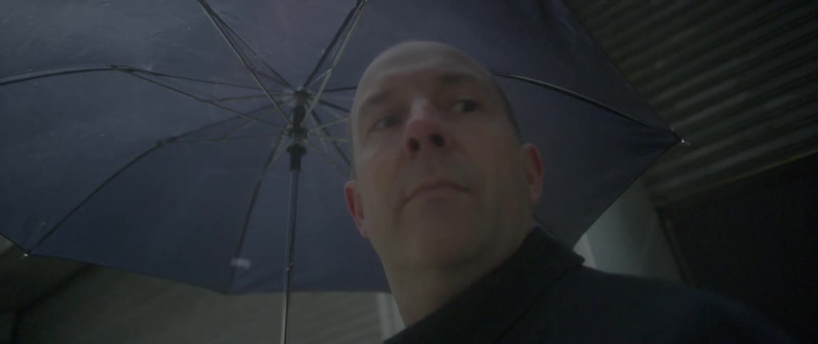 A man holding an umbrella looks around
