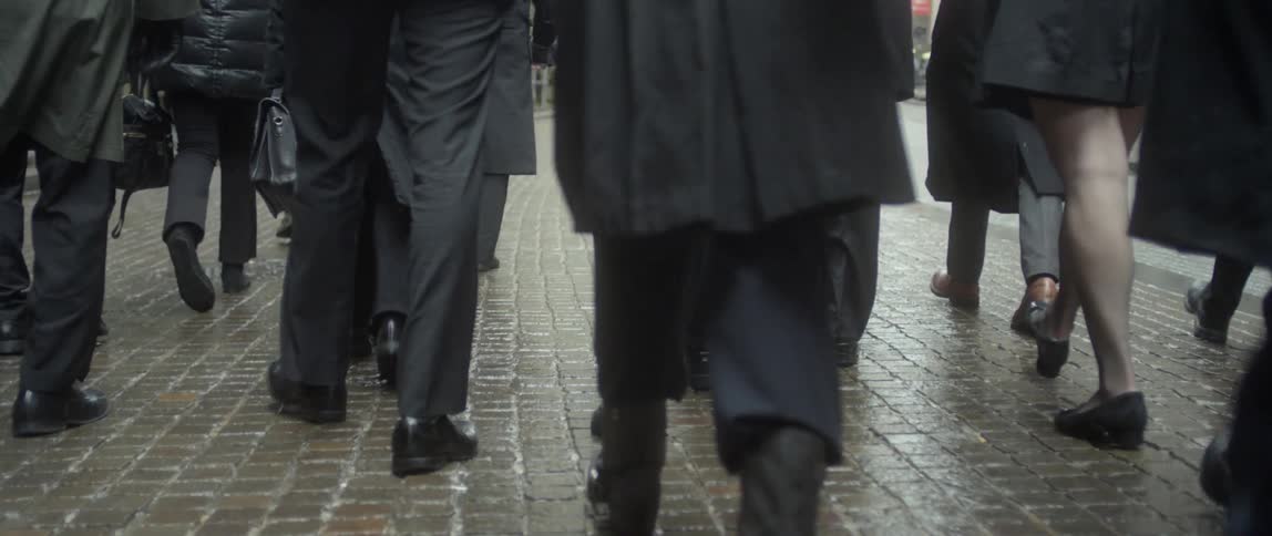 People are walking together in the rain on a sidewalk