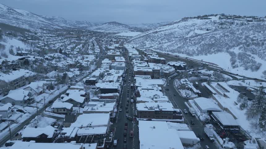 Traffic drives down main street in a mountain town covered in snow