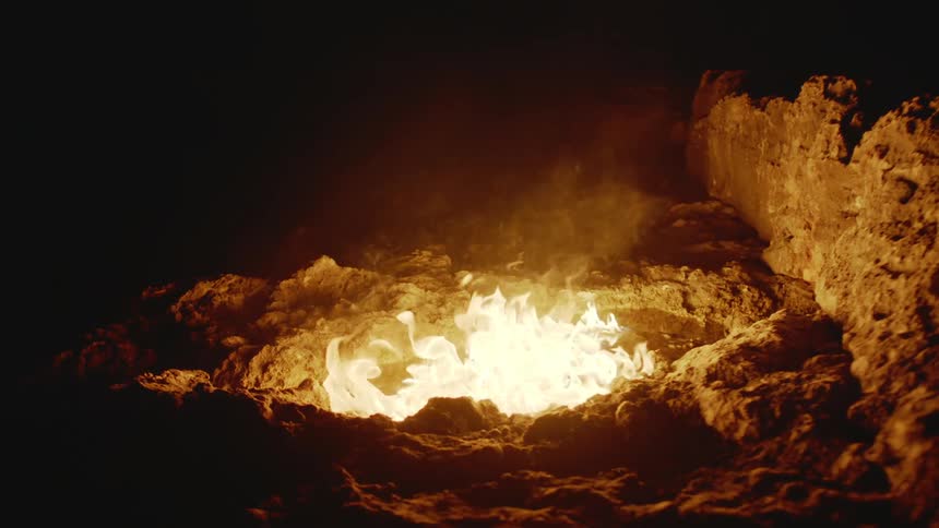 Man lights pool of liquid in dip on rocky ground at night