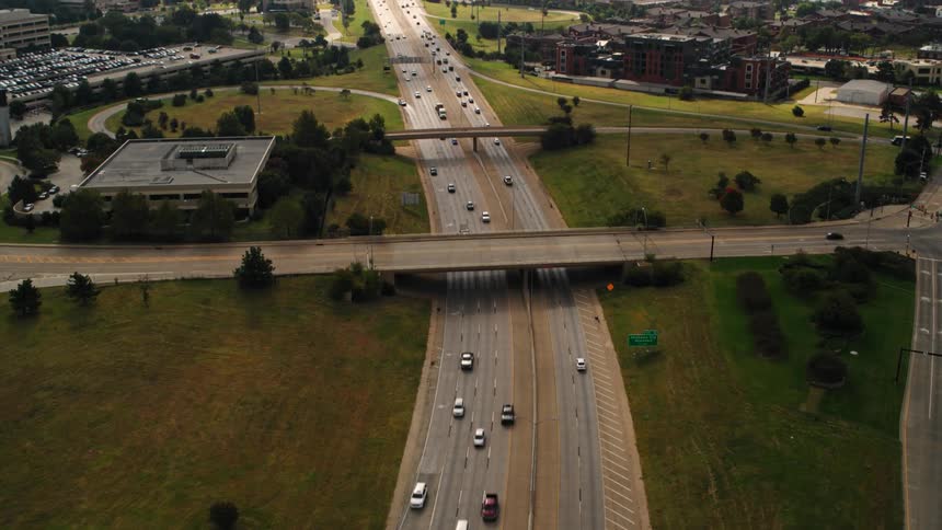 Traffic moves on freeways through town with many buildings and parking lots