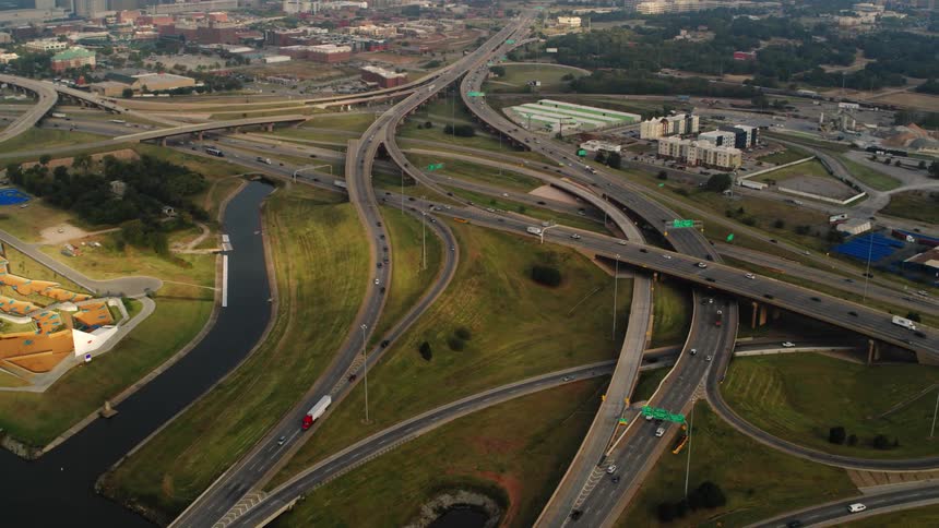Traffic moves along network of highways near riverwith city downtown in the background