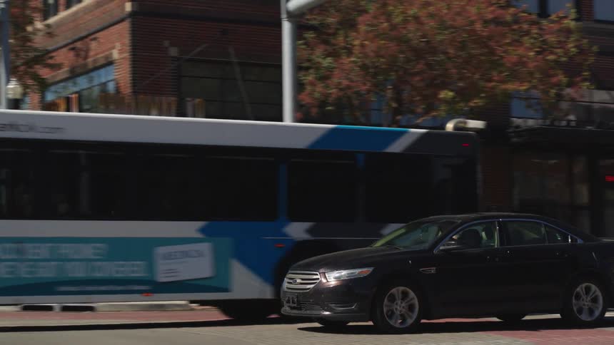A black car driving into an intersection waiting for cars to pass and then turning