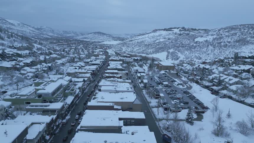 An aerial of a snow covered city between snowy hillsides