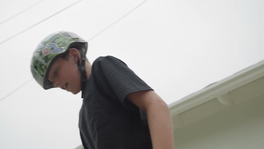 Boy skateboards on vert ramp in yard next to building