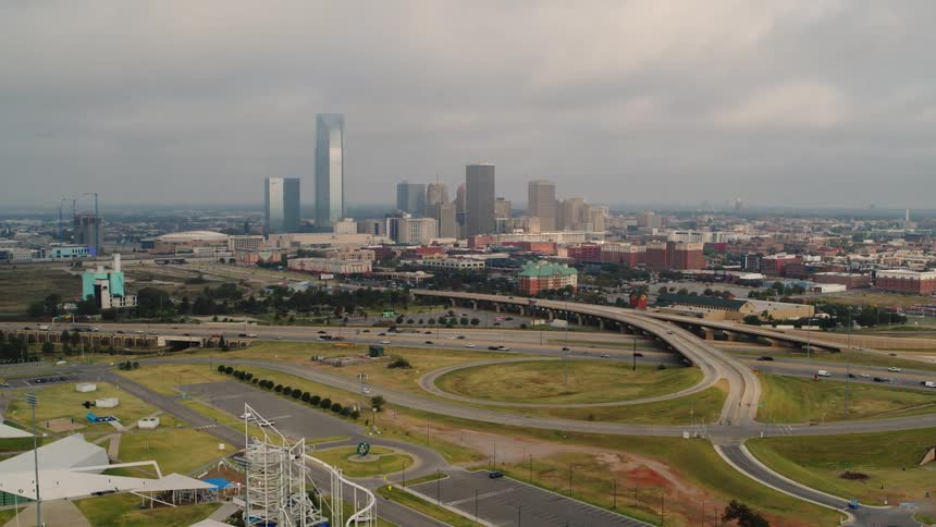 Traffic moves on highways on the outskirts of town with tall buildings and skyscrapers on the city skyline