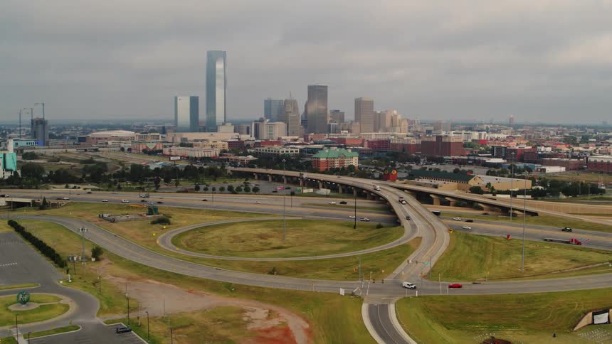 Cars driving on a freeway with a city skyline with high rise office buildings in the distance
