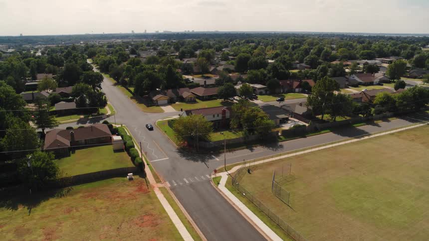 An aerial view of a suburb area with a large baseball field and streets