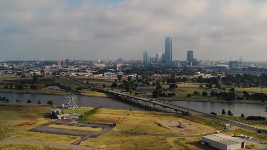 An upward aerial of a city in the distance with a bridge running over a waterway