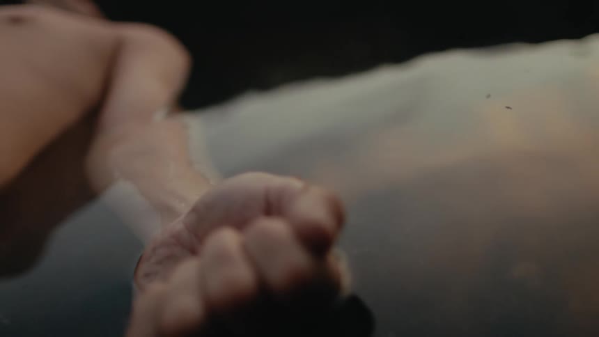 A persons arm and body submerged in water with their hand in a fist