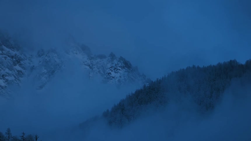 Fog and a heavy layer of snow cover a mountain range