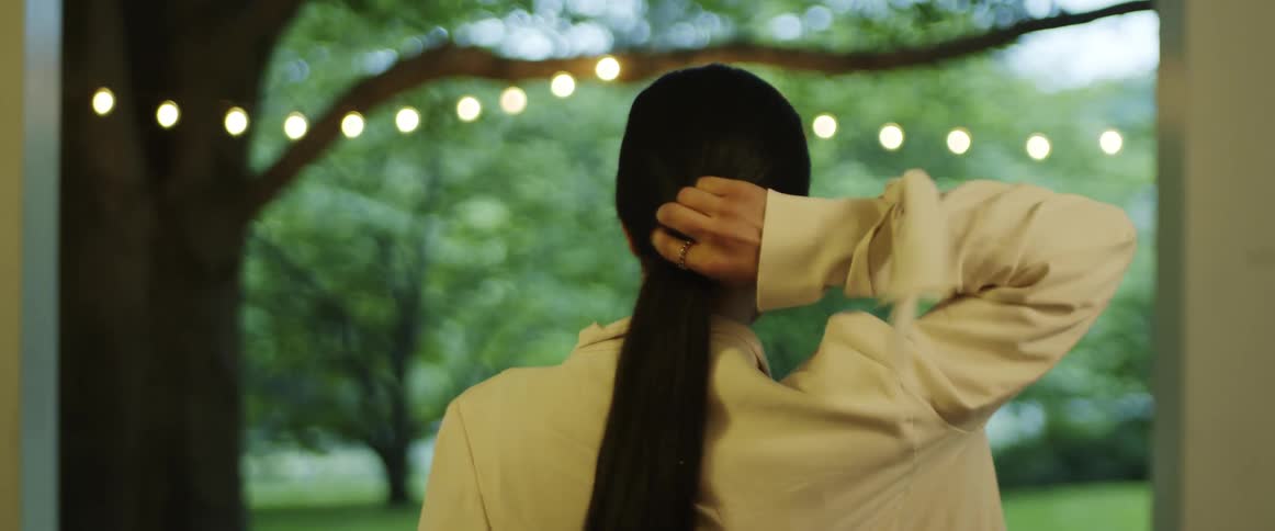 A woman walking outside taking her hair out ofa hair tie