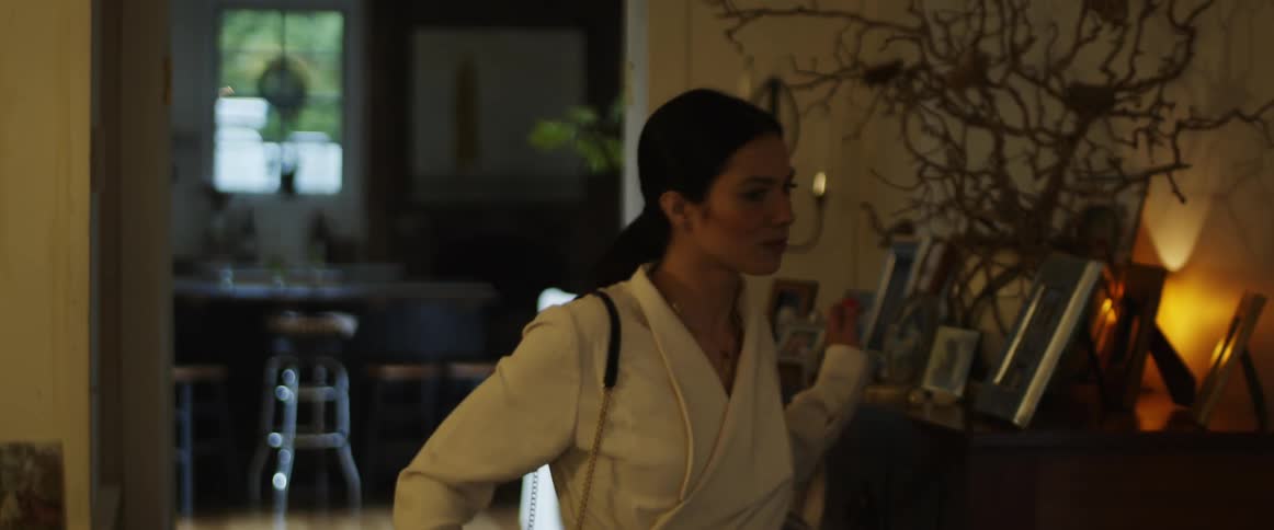 A woman takes off her earrings and purse after getting home