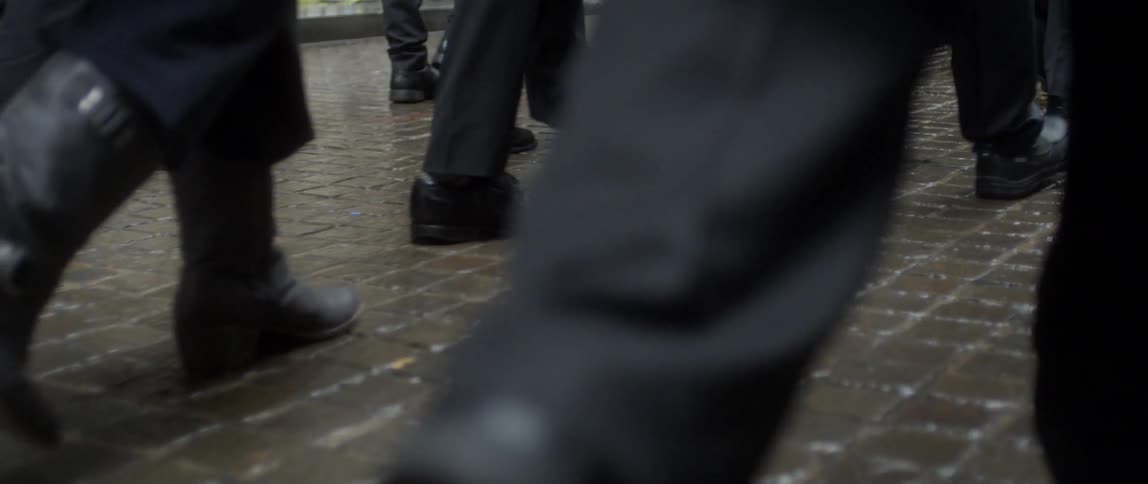 People are walking on a sidewalk in the rain