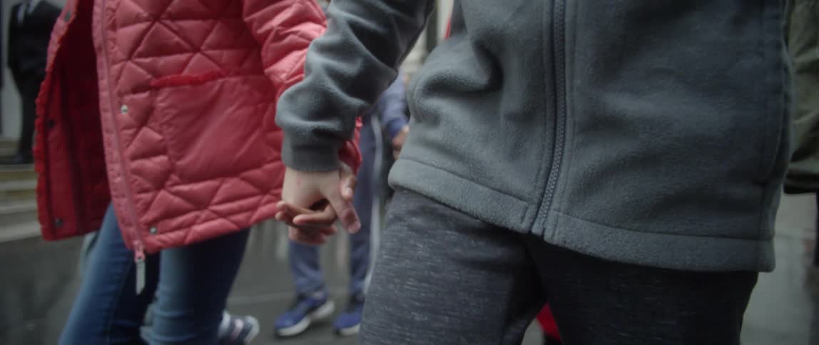 People are holding hands walking on a sidewalk