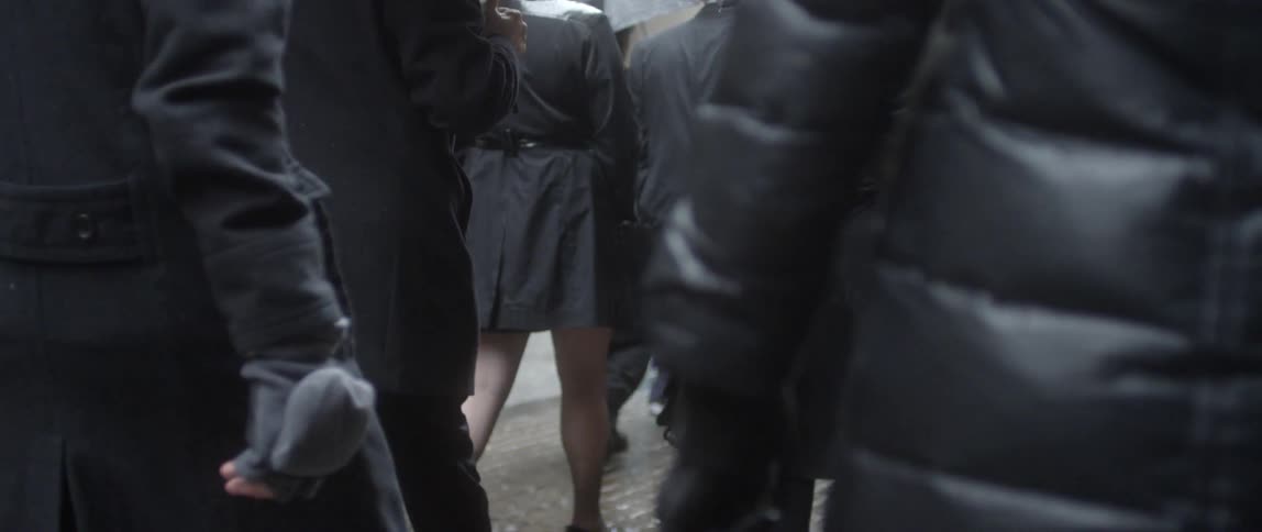 A crowd of people wearing black cold weather clothing walks