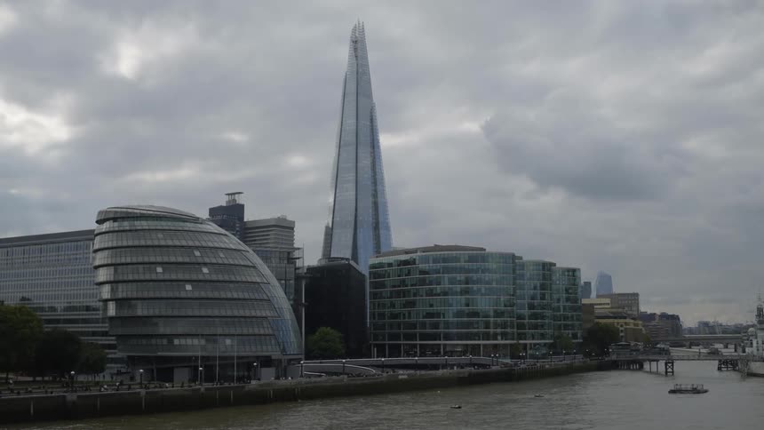 Tall buildings loom over a waterway in a metropolis on a cloudy day