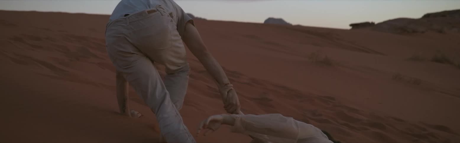 A man dragging a woman through dunes