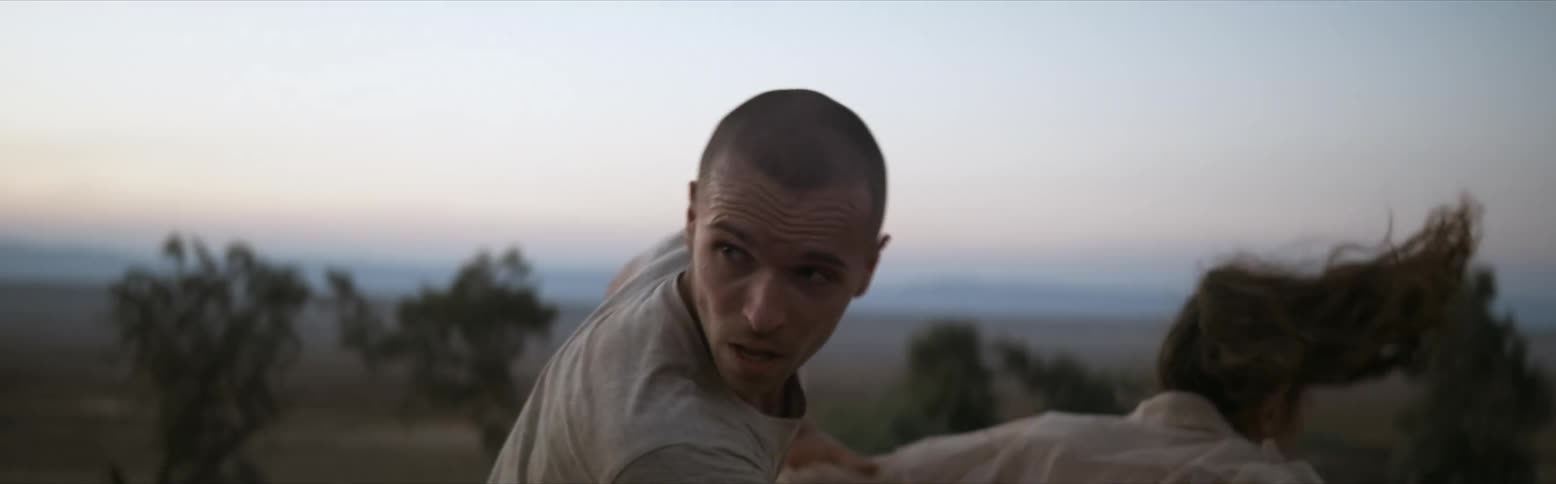A man runs after a woman walking away and grabs her and drags her and she fights and struggles to get away