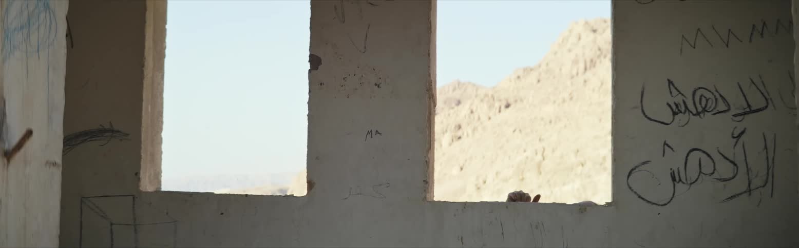 A woman stretching and jumping in an open window frame of a building