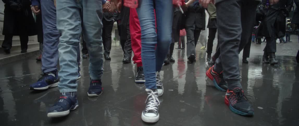 Protesters march on a rainy city sidewalk