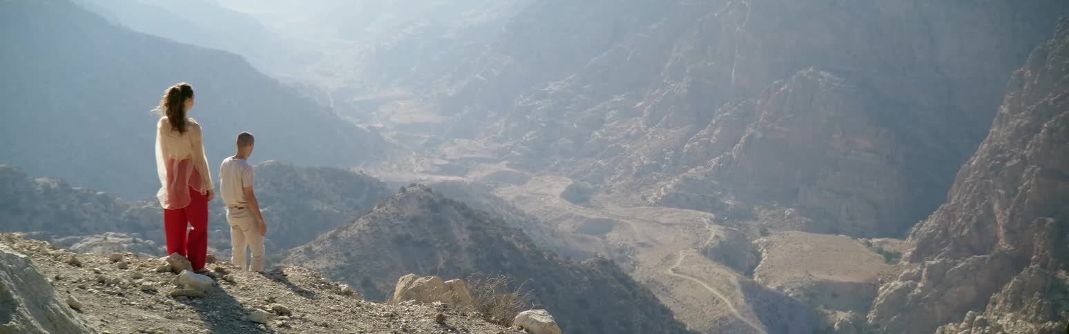 Young couple standing atop a mountain looking down a valley in the desert