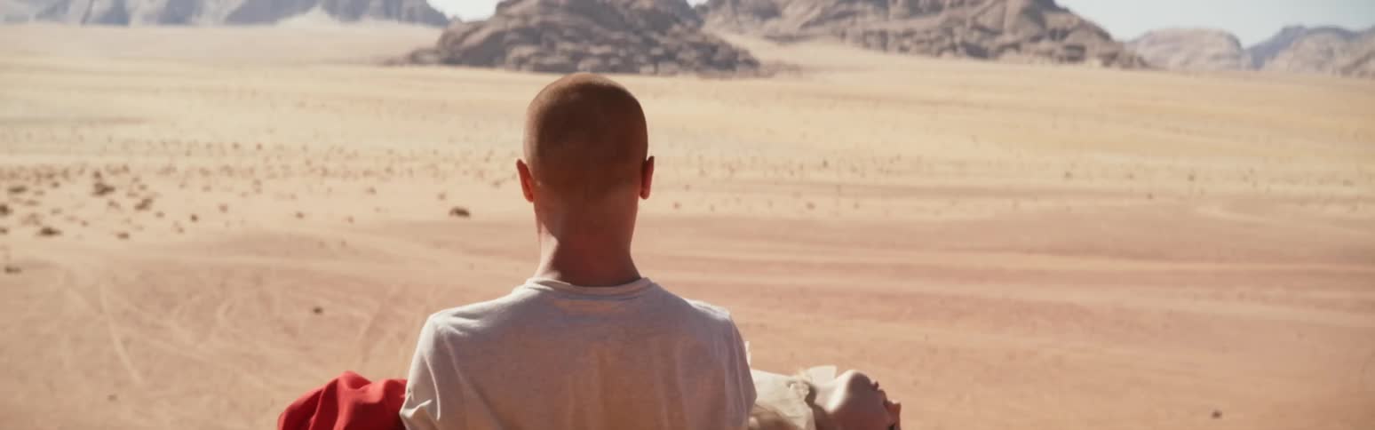 Man and woman stranded in desert woman collapses man lifts her up and carries for her away as he searches for help