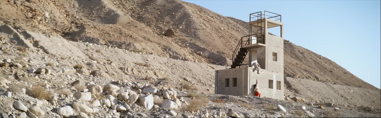 Two people in the distance crawling and leaning against a lone structure