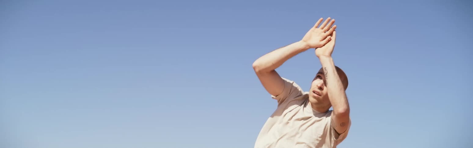 A man holding his hands up to shield the sun in the desert