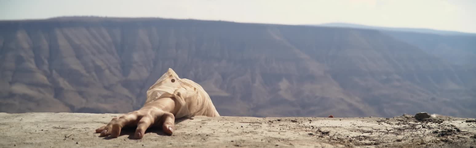 A persons hands grabbing at dirt over a ledge