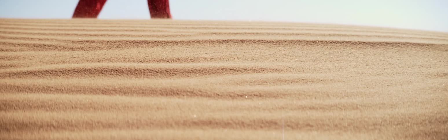 An up close of desert sand as people walk by in the distance