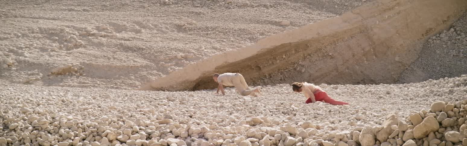 Two people crawling up a rocky incline