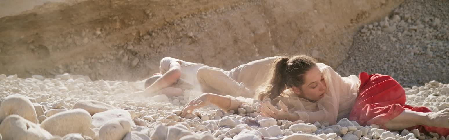 A man and a woman are lying on the ground and are mysteriously being pulled across rocks in the desert