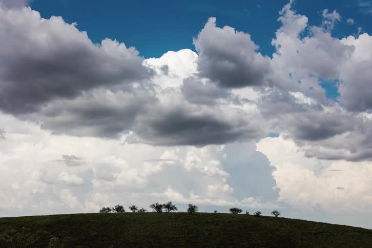Giant cumulous clouds are forming and flowing in the blue sky over flatland