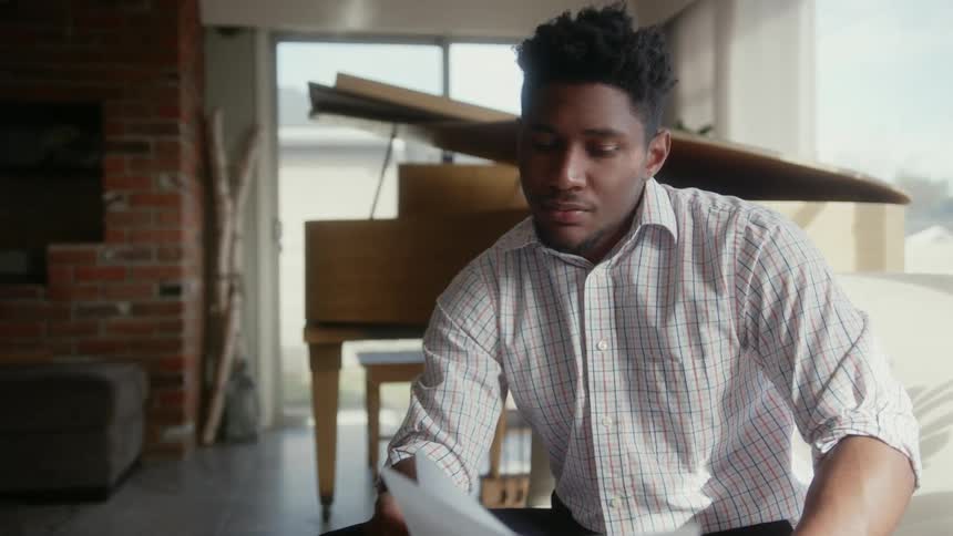 A man is sitting and shaking his head while looking at documents
