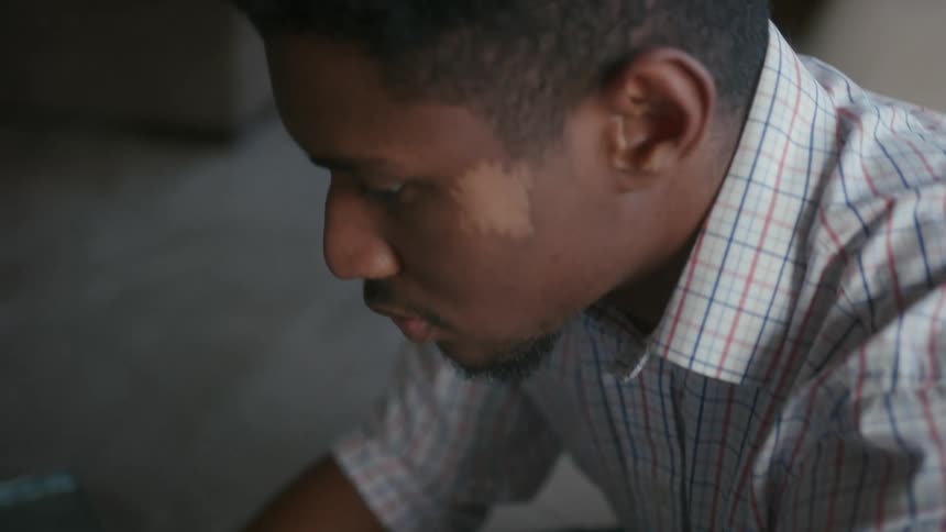 A man is sitting at a table typing on a laptop computer