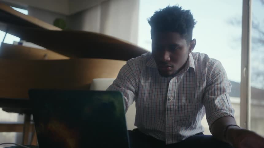 A man shifting around papers before working on laptop