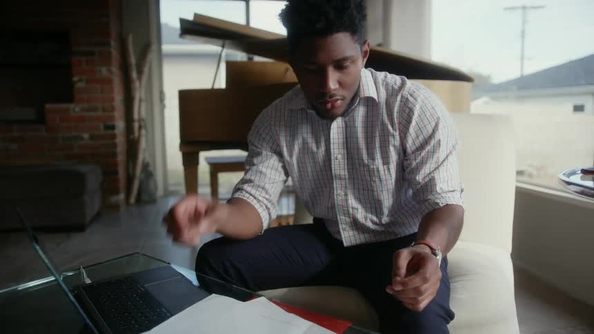 A man sitting looking through papers putting his hand on his head in frustration