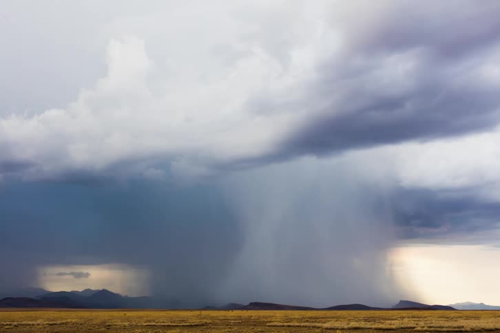 Rain is falling and lightning is striking from storm clouds over flatlands