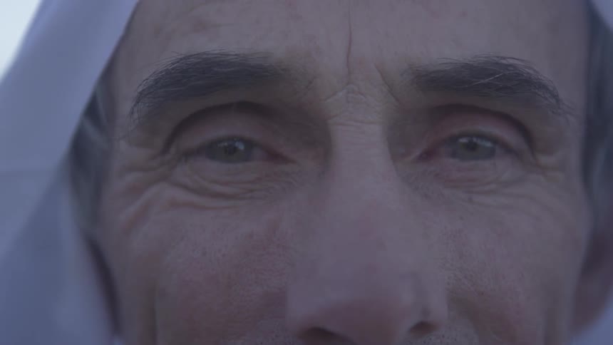 A man is wearing a white head covering