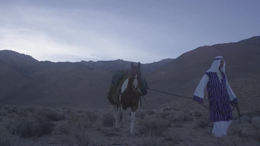 Man leading his horse  as they walk in the wilderness