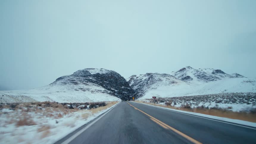 A highway runs past snow capped mountains