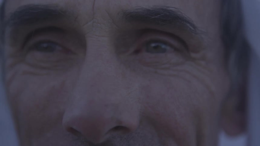A breeze rustling a scarf on an elderly man's head as he gazes into the distance
