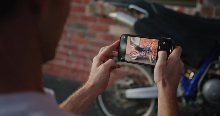 A man takes a photo of his motorcycle with his smartphone