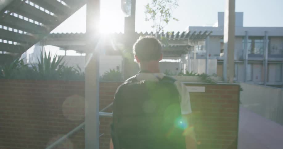 Man wearing backpack exits building and walks down stairs