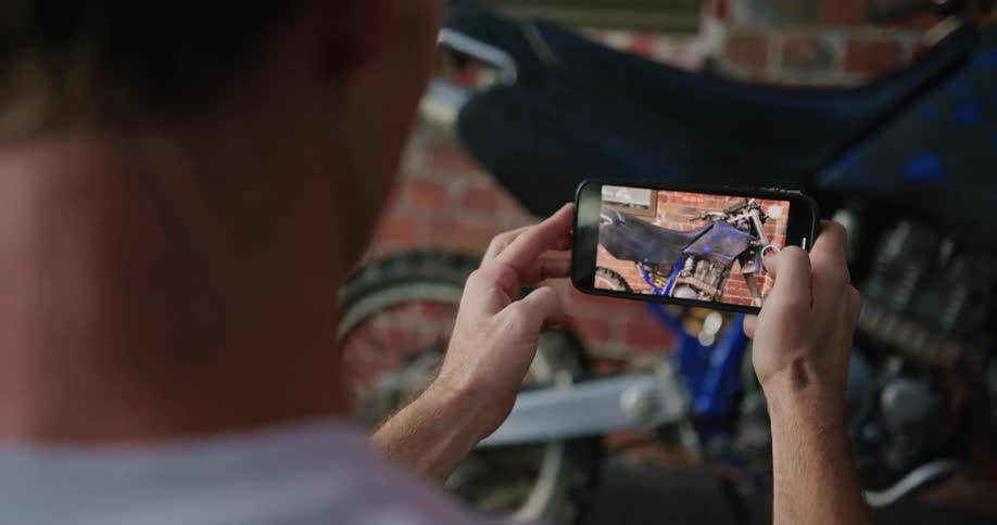 A man uses his phone to record video of his motorcycle