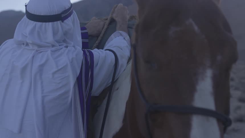 A man adjusting a pack on his horse's back
